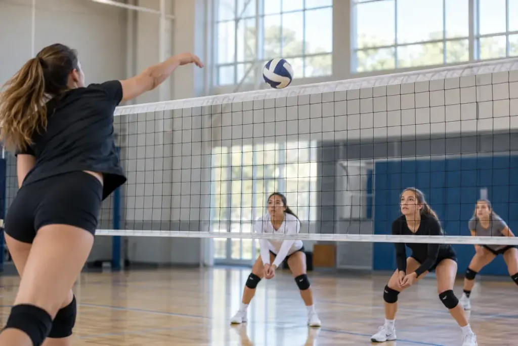 A volleyball just crossing above the net during a serve in a well-lit indoor court.