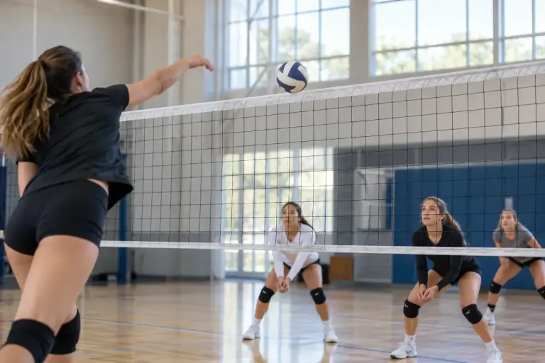 A volleyball just crossing above the net during a serve in a well-lit indoor court.